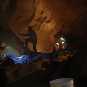 shilouette photo of a caver sandblasting graffiti off of a cave wall